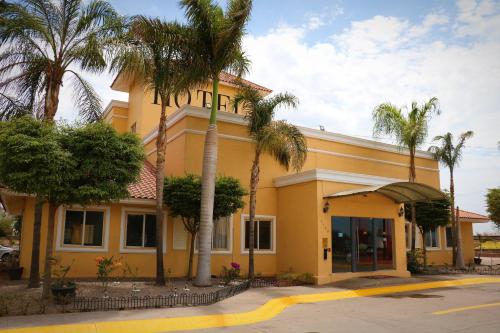 a yellow building with palm trees in front of it at Zar Culiacan in Culiacán