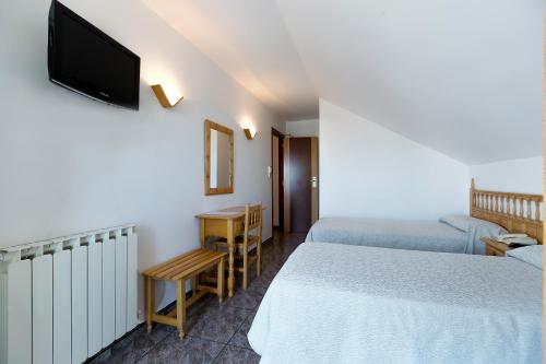 a hotel room with two beds and a flat screen tv at Hotel Brisa in A Lanzada