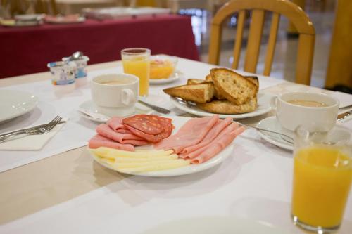 a table with a plate of cheese and bread and orange juice at Hotel Brisa in A Lanzada