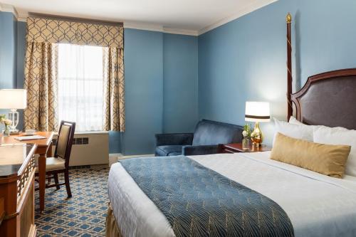 a hotel room with a bed, desk, chair, and lamp at Francis Marion Hotel in Charleston