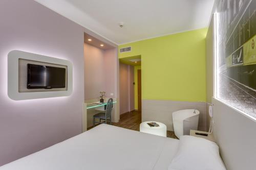Pokój z łóżkiem i telewizorem na ścianie w obiekcie Kleos Hotel Milano w Mediolanie