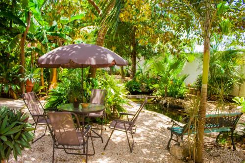 a table and chairs with an umbrella in a garden at Casa De Los Pájaros - B&B in Valladolid
