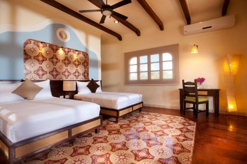 a bedroom with two beds and a table and a window at Hacienda Viva Sotuta de Peón in Tecoh