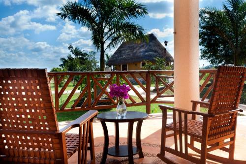 two chairs and a table with a vase of flowers on a porch at Hacienda Viva Sotuta de Peón in Tecoh