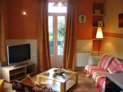 a living room with a couch and a tv at La Vallée in Le Mont-Dore