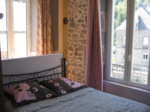 a bedroom with a bed and two windows at La Vallée in Le Mont-Dore