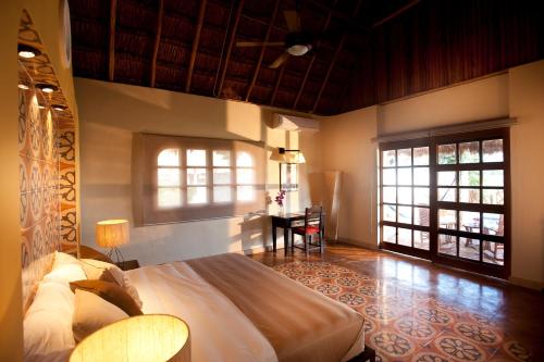 a bedroom with a bed and a desk and windows at Hacienda Viva Sotuta de Peón in Tecoh