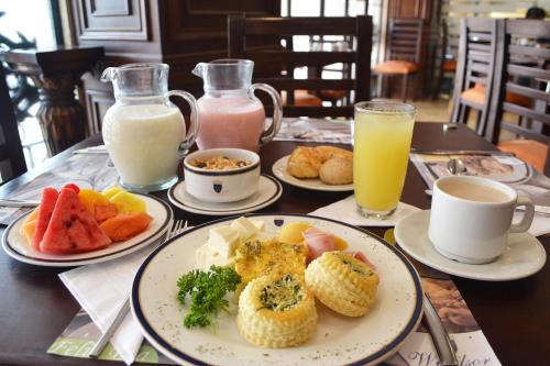 a table with plates of breakfast foods and drinks at Hotel Windsor Barranquilla in Barranquilla