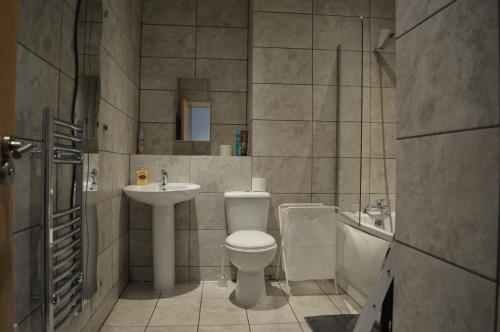 a bathroom with a toilet and a sink and a tub at Spacious Shude Hill Apartment With Balcony in Manchester