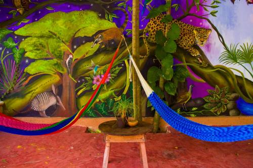 a hammock in front of a painting of a jungle at Casa De Los Pájaros - B&B in Valladolid