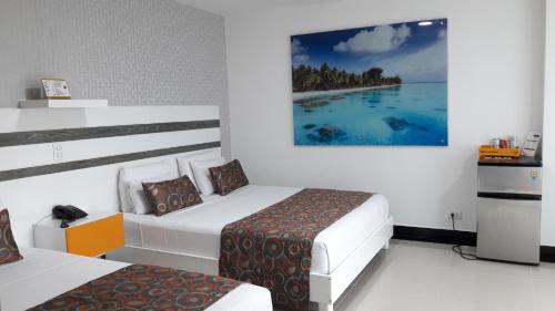 a bedroom with two beds and a painting on the wall at Hotel Genova Prado in Barranquilla
