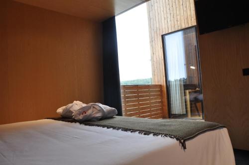 a bed in a room with a large window at Cró Hotel Rural in Rapoula do Côa