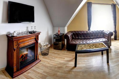 a living room with a leather couch and a fireplace at Penzion Tillerova vila in Lázně Bohdaneč