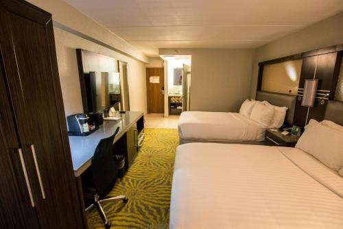 a hotel room with two beds and a desk at Holiday Inn Dallas-Richardson by IHG in Richardson