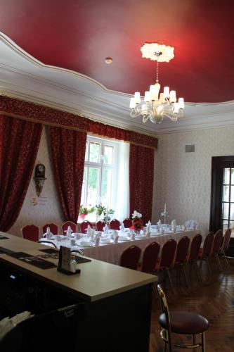 Habitación con una mesa larga con sillas y una lámpara de araña. en Pałac Ogrodowa, en Tarnowskie Góry