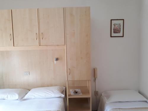 a bedroom with two beds and a cabinet at Hotel Villa Dina in Lido di Jesolo