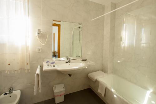 La salle de bains est pourvue d'un lavabo, d'une baignoire et de toilettes. dans l'établissement Hotel Brisa da Lanzada, à A Lanzada