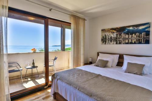 ein Schlafzimmer mit einem großen Bett und einem großen Fenster in der Unterkunft Villa Rijeka Rezevici in Petrovac na Moru