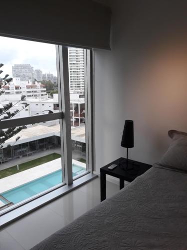 Un dormitorio con una cama y una ventana grande. en Apartamento Punta del Este Arenas, en Punta del Este