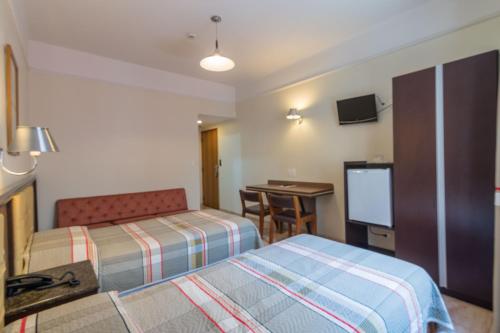 a hotel room with two beds and a television at Soneca Plaza Hotel in Sao Paulo