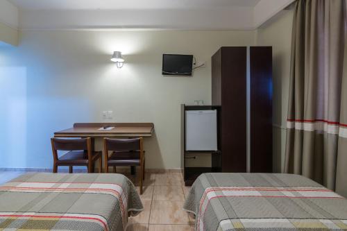 a room with two beds and a table and a desk at Soneca Plaza Hotel in Sao Paulo