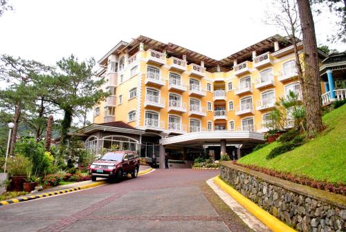a car parked in front of a large yellow building at Hotel Elizabeth - Baguio in Baguio