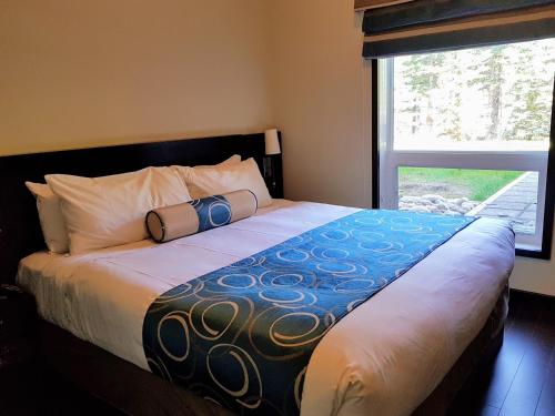 a bedroom with a large bed with a large window at Paradise Resort Club and Spa in Canmore