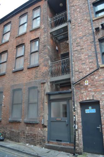 a brick building with a door and a balcony at Spacious Shude Hill Apartment With Balcony in Manchester