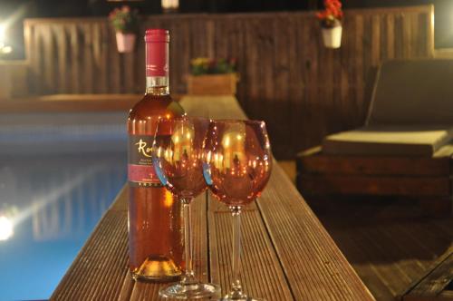 a bottle of wine sitting next to three wine glasses at Villa Imerti Kiotari in Kiotari