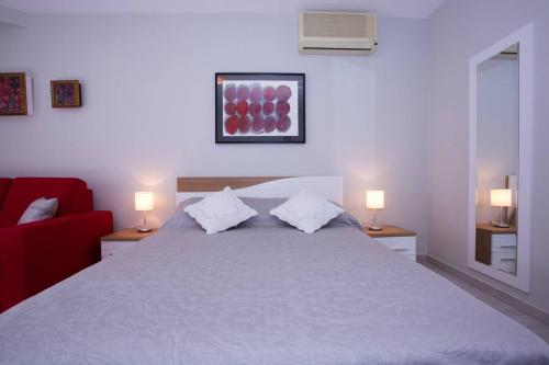 a bedroom with a large white bed with two lamps at Apartments Daisy in Dubrovnik
