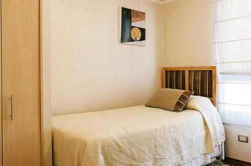 - une chambre avec un lit et un oreiller dans l'établissement Departamentos Alto Moneda, à Santiago