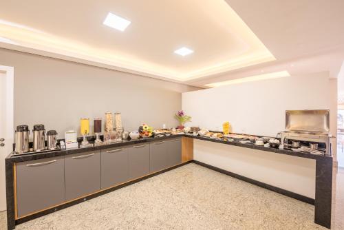 a large kitchen with a long counter with food at Prime Hotel Ponta Porã in Ponta Porã