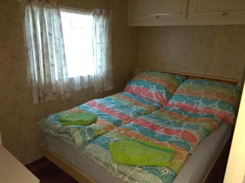 a bed with a colorful quilt and a window at Mobilheim Vyhlídka Camp Výrovice in Výrovice