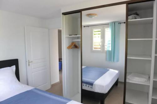 Dormitorio pequeño con cama y espejo en Villa Yona, en Sainte-Anne