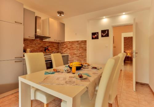 a kitchen and dining room with a white table and chairs at Apartments Dora Victoria Dream in Medulin