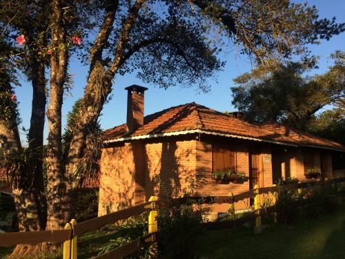una vieja casa de ladrillo con chimenea y valla en Chales Encanto Suíço, en Monte Verde
