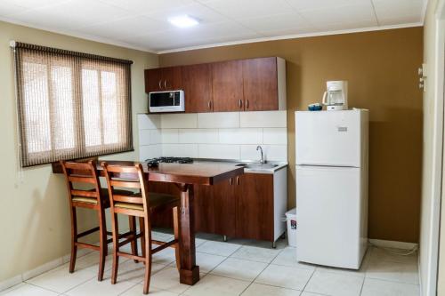 a kitchen with a table and a white refrigerator at Coconut Inn in Palm-Eagle Beach