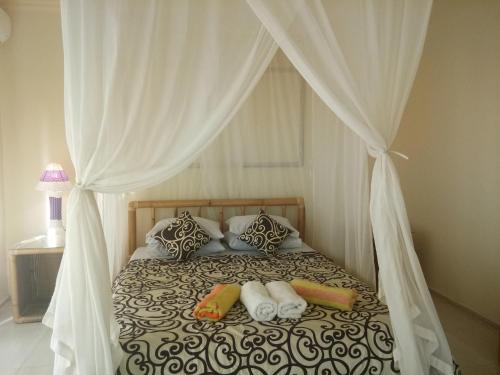 - un lit avec des rideaux blancs et des oreillers dans l'établissement Kerta Family Bed and Breakfast, à Ubud