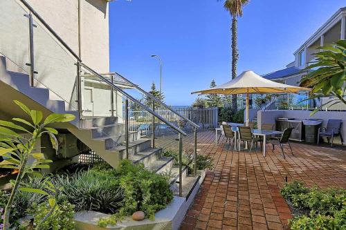 
a patio area with a patio table and umbrella at Beachfront @ Scarbs in Perth

