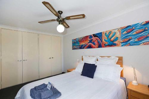 Beachfront @ Scarbs في بيرث: غرفة نوم بسرير أبيض مع مروحة سقف