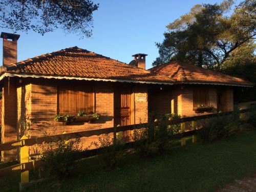 a wooden house with a fence in front of it at Chales Encanto Suíço in Monte Verde