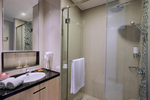 スラバヤにあるThe Southern Hotel Surabaya Formerly Ibis Styles Surabaya Jemursariのバスルーム(洗面台、ガラス張りのシャワー付)