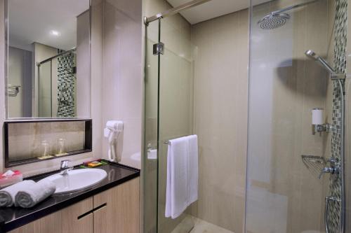 a bathroom with a sink and a glass shower at The Southern Hotel Surabaya Formerly Ibis Styles Surabaya Jemursari in Surabaya