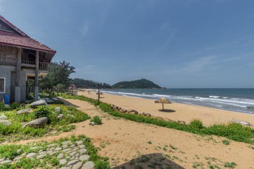 a beach with a building and an umbrella on it at Quỳnh Viên Resort in Dương Luật