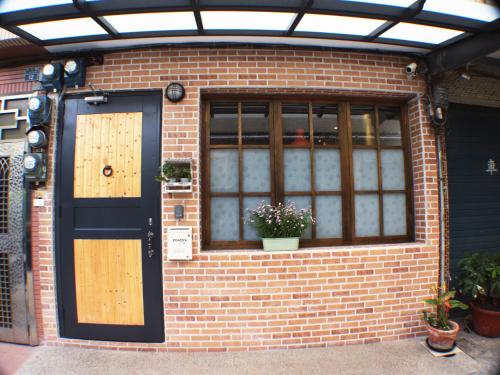 een bakstenen gebouw met een blauwe deur en een raam bij Knock Knock Hostel in Kaohsiung