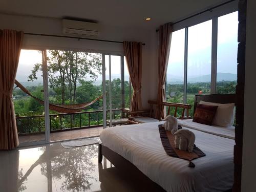 a bedroom with a bed and a balcony with a hammock at Chang Pai Hill in Pai