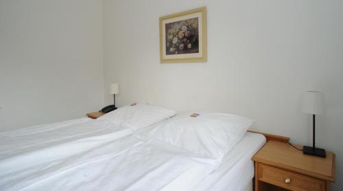 a white bed with two lamps on top of it at Hotel Waldesruh in Düsseldorf