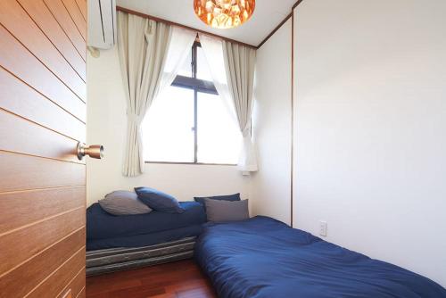 a bed in a room with a window at Guest House Umusan in Nago