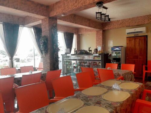 un comedor con mesas y sillas naranjas, una mesa y un sillón en RSG Microhotel, en General Santos