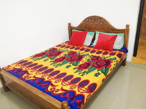 a bed with a colorful comforter and red pillows at 20 House Arugam in Arugam Bay